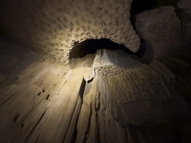 منظر داخلي لكهف الهوته في سلطنة عمان يظهر التكوينات الصخرية الطبيعية والممرات المضاءة في أجواء جيولوجية مذهلة.