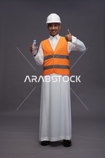 عامل سعودي بمعدات السلامة يحمل زجاجة ماء