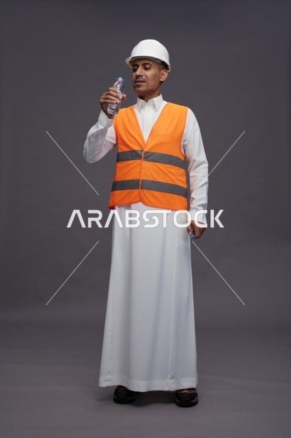 عامل سعودي بمعدات السلامة يحمل زجاجة ماء