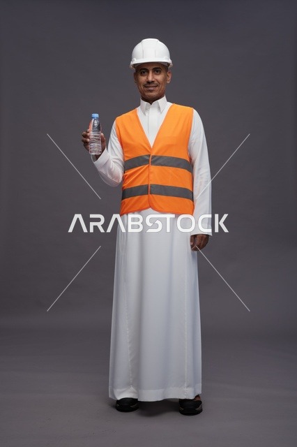 عامل سعودي بمعدات السلامة يحمل زجاجة مياه