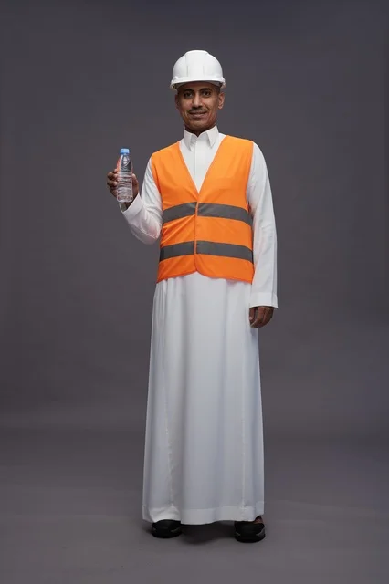 عامل سعودي بمعدات السلامة يحمل زجاجة مياه