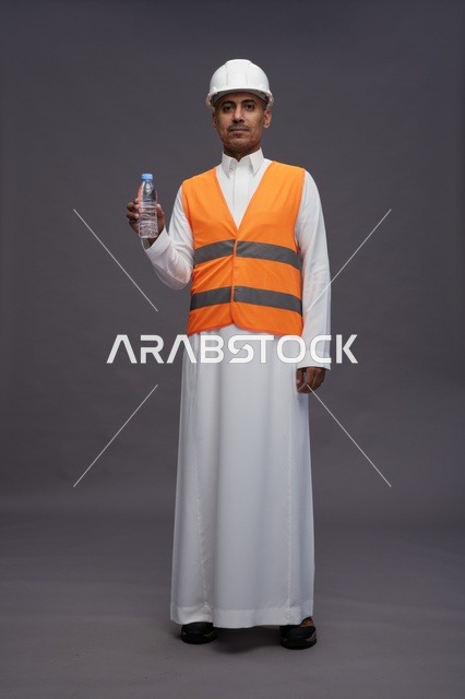عامل سعودي بمعدات السلامة يحمل زجاجة ماء