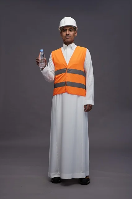 عامل سعودي بمعدات السلامة يحمل زجاجة ماء