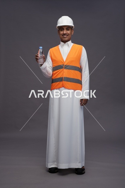 عامل سعودي بمعدات السلامة يحمل زجاجة ماء
