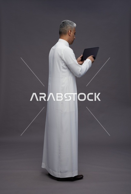 رجل سعودي يتفاعل مع جهاز لوحي بالزي التقليدي
