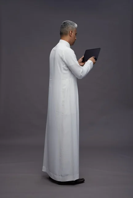 رجل سعودي يتفاعل مع جهاز لوحي بالزي التقليدي