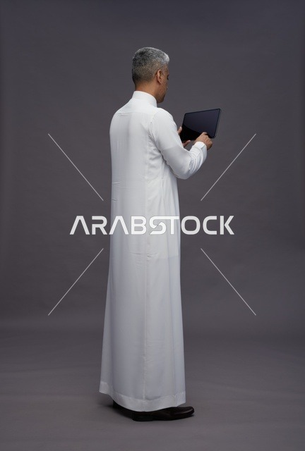 رجل سعودي يتفاعل مع جهاز لوحي بالزي التقليدي