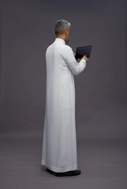 رجل سعودي يتفاعل مع جهاز لوحي بالزي التقليدي
