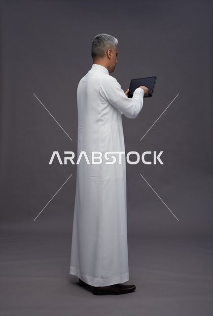 رجل سعودي يتفاعل مع جهاز لوحي بالزي التقليدي