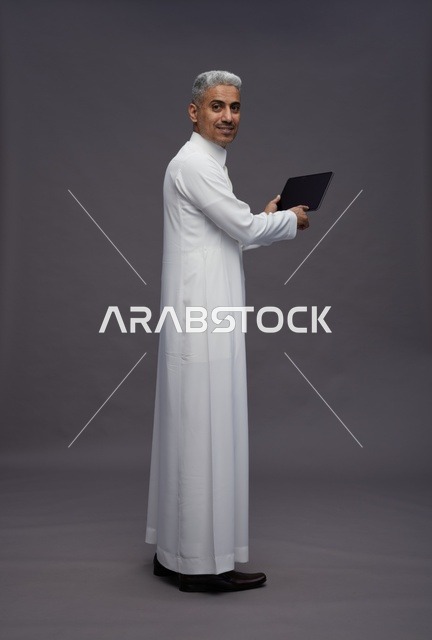 رجل سعودي يتفاعل مع جهاز لوحي بالزي التقليدي