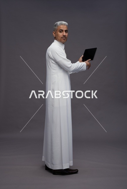 رجل سعودي يتفاعل مع جهاز لوحي بالزي التقليدي