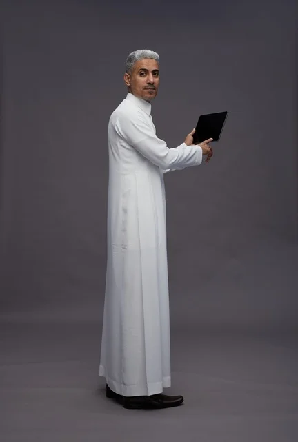 رجل سعودي يتفاعل مع جهاز لوحي بالزي التقليدي