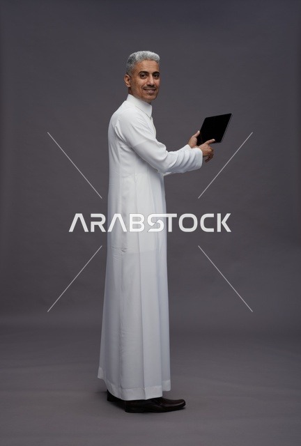 رجل سعودي يتفاعل مع جهاز لوحي بالزي التقليدي