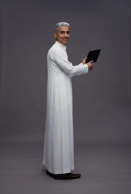 رجل سعودي يتفاعل مع جهاز لوحي بالزي التقليدي