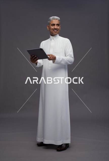 رجل سعودي يتفاعل مع جهاز لوحي بالزي التقليدي