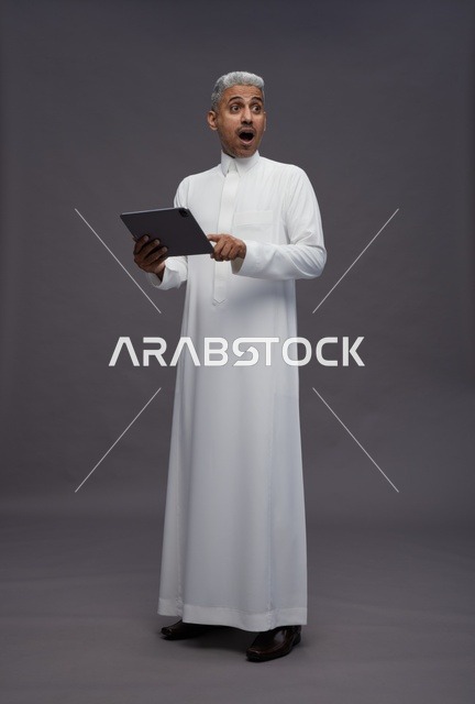 رجل سعودي يتفاعل مع جهاز لوحي بالزي التقليدي