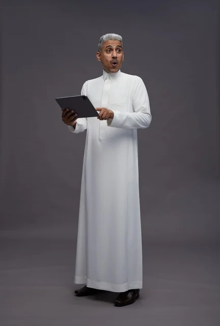 رجل سعودي يتفاعل مع جهاز لوحي بالزي التقليدي