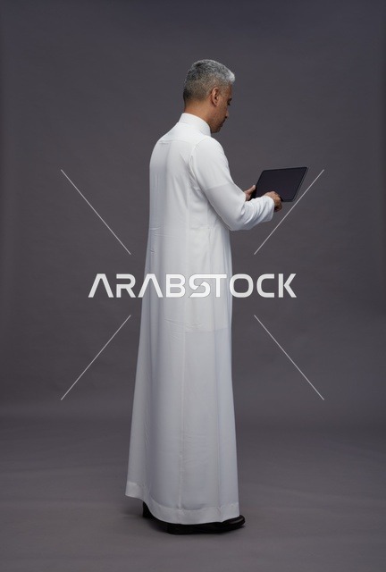 رجل سعودي يتفاعل مع جهاز لوحي بالزي التقليدي