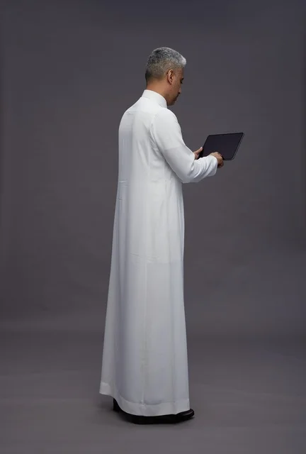 رجل سعودي يتفاعل مع جهاز لوحي بالزي التقليدي