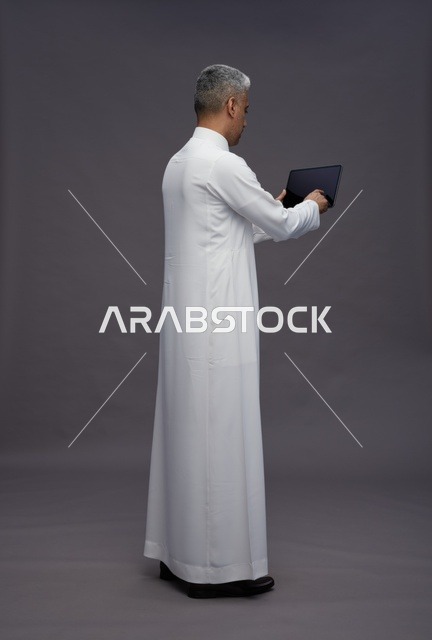 Saudi man interacting with a tablet in traditional attire