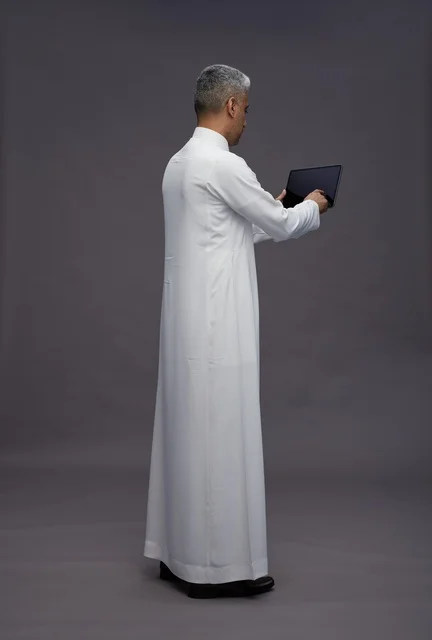 رجل سعودي يتفاعل مع جهاز لوحي بالزي التقليدي