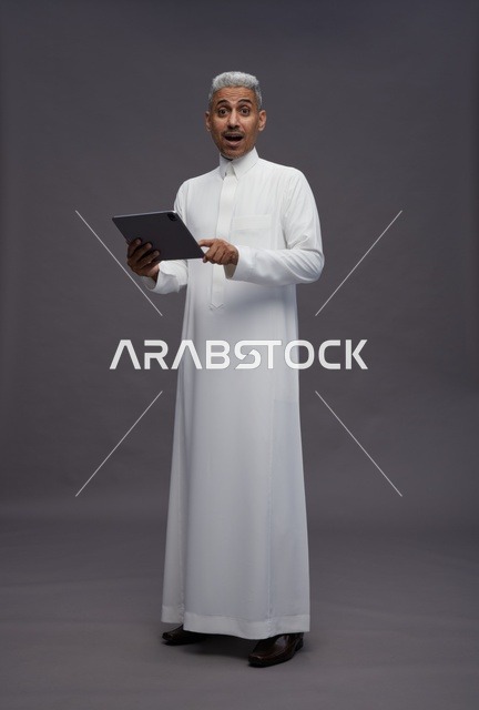 رجل سعودي يتفاعل مع جهاز لوحي بالزي التقليدي