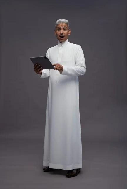 رجل سعودي يتفاعل مع جهاز لوحي بالزي التقليدي