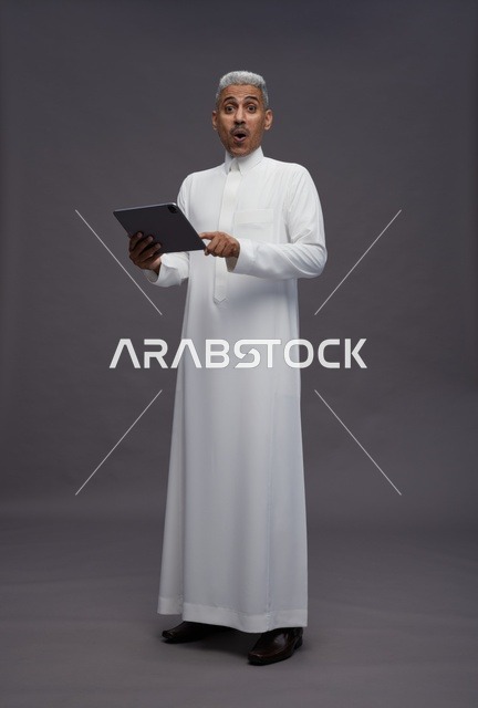 رجل سعودي يتفاعل مع جهاز لوحي بالزي التقليدي