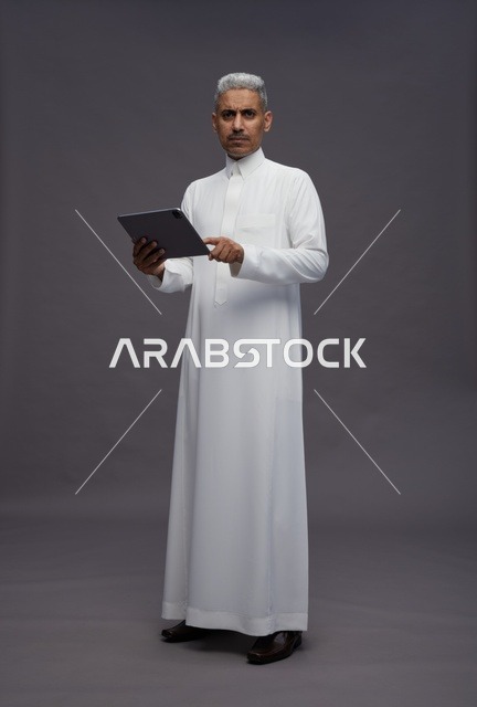 رجل سعودي يتفاعل مع جهاز لوحي بالزي التقليدي