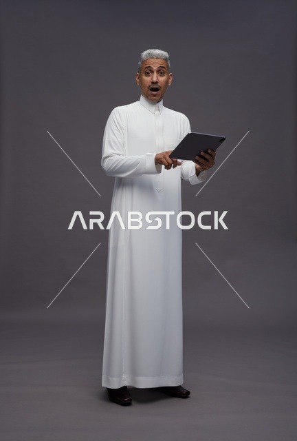 رجل سعودي يتفاعل مع جهاز لوحي بالزي التقليدي