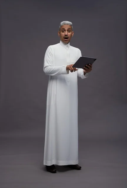 رجل سعودي يتفاعل مع جهاز لوحي بالزي التقليدي