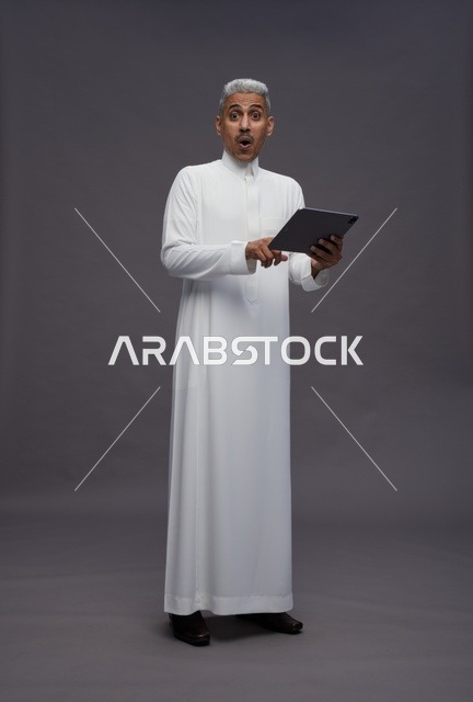 رجل سعودي يتفاعل مع جهاز لوحي بالزي التقليدي