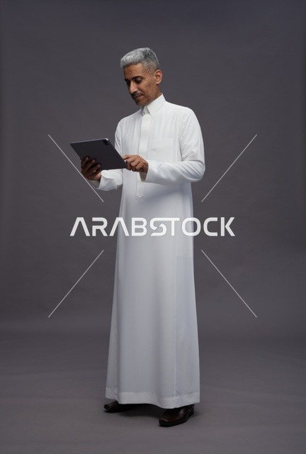 رجل سعودي يتفاعل مع جهاز لوحي بالزي التقليدي
