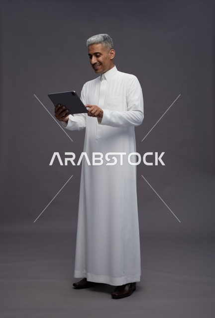 رجل سعودي يتفاعل مع جهاز لوحي بالزي التقليدي