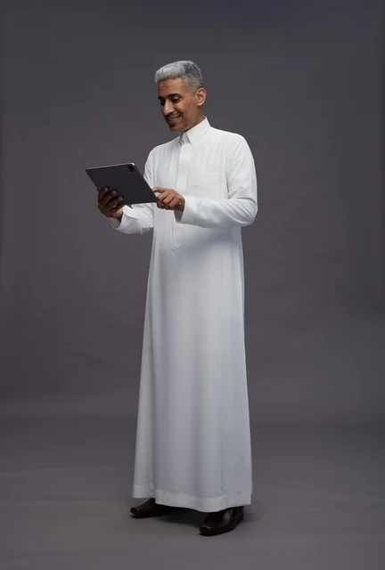 رجل سعودي يتفاعل مع جهاز لوحي بالزي التقليدي