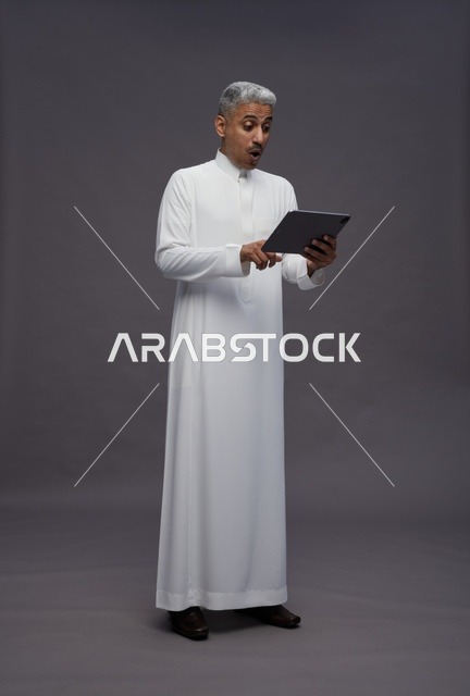 رجل سعودي يتفاعل مع جهاز لوحي بالزي التقليدي