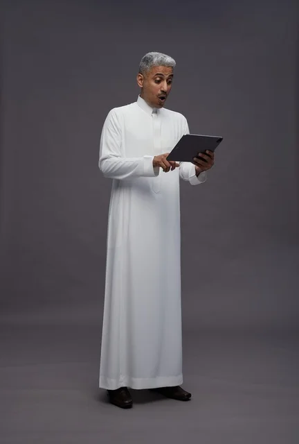 رجل سعودي يتفاعل مع جهاز لوحي بالزي التقليدي