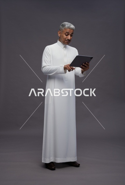 رجل سعودي يتفاعل مع جهاز لوحي بالزي التقليدي