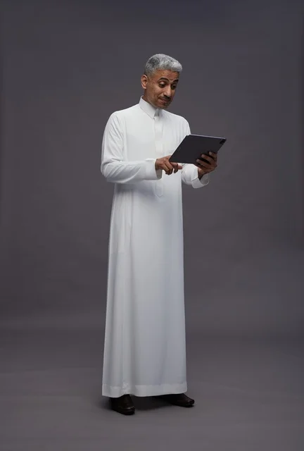 رجل سعودي يتفاعل مع جهاز لوحي بالزي التقليدي