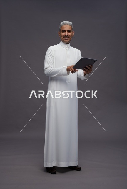 رجل سعودي يتفاعل مع جهاز لوحي بالزي التقليدي