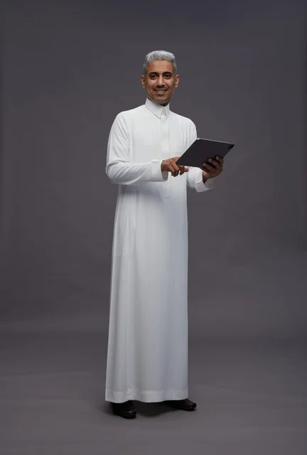 رجل سعودي يتفاعل مع جهاز لوحي بالزي التقليدي