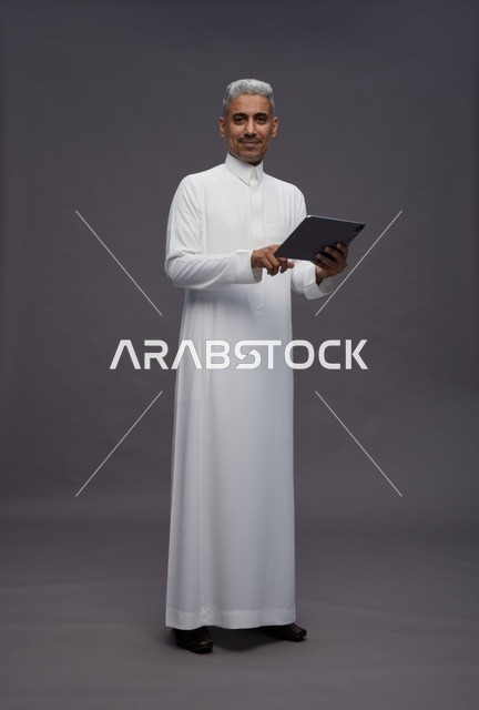 رجل سعودي يتفاعل مع جهاز لوحي بالزي التقليدي