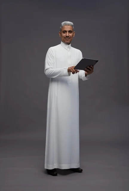 رجل سعودي يتفاعل مع جهاز لوحي بالزي التقليدي