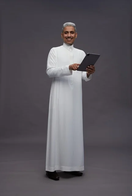 رجل سعودي يتفاعل مع جهاز لوحي بالزي التقليدي