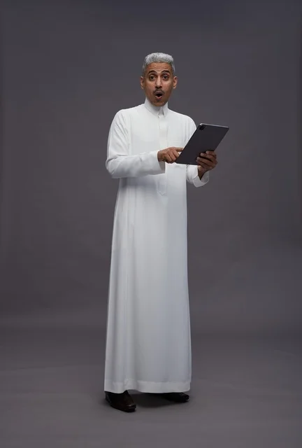 رجل سعودي يتفاعل مع جهاز لوحي بالزي التقليدي