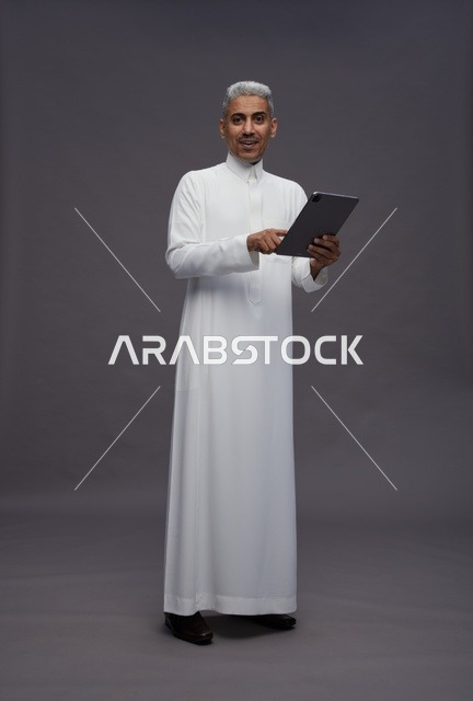 رجل سعودي يتفاعل مع جهاز لوحي بالزي التقليدي