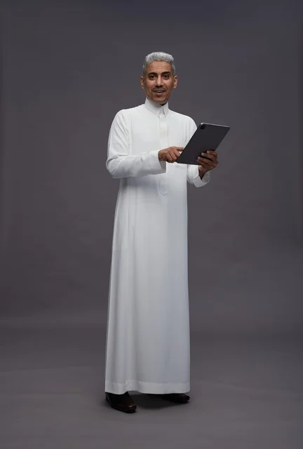 رجل سعودي يتفاعل مع جهاز لوحي بالزي التقليدي