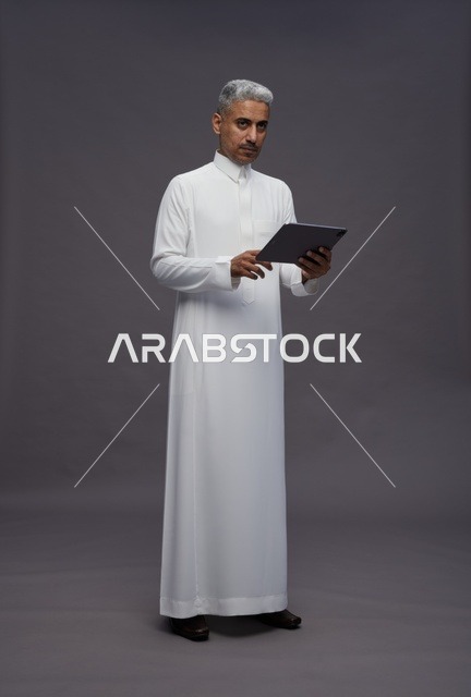 رجل سعودي يتفاعل مع جهاز لوحي بالزي التقليدي