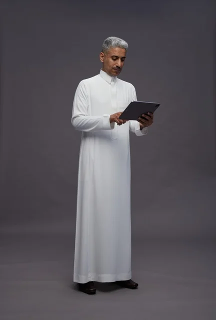 رجل سعودي يتفاعل مع جهاز لوحي بالزي التقليدي