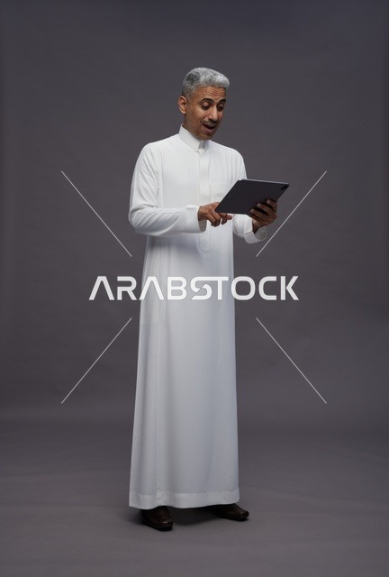 رجل سعودي يتفاعل مع جهاز لوحي بالزي التقليدي
